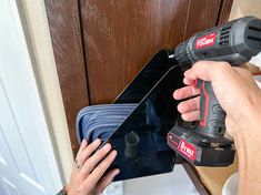 a person using a cordless drill to fix a door