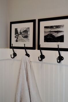 two black and white pictures hanging on the wall next to towel racks with hooks in front of them