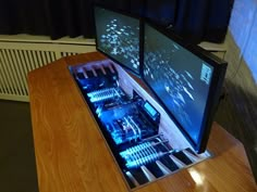 two computer monitors sitting on top of a wooden table