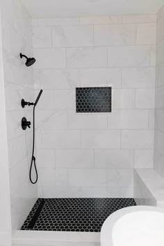 a white bathroom with black and white tile on the shower wall, toilet and sink