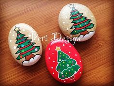 three painted rocks with christmas trees on them