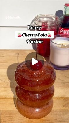 a cherry cola sitting on top of a wooden table next to some jars and candles