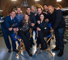 a group of people posing for a photo in a room with blue walls and chairs