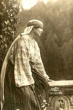 an old photo of a woman sitting on a ledge