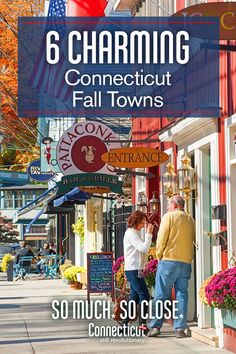 two people standing on the sidewalk talking to each other in front of stores with flags and flowers