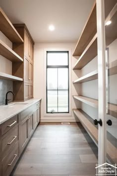 an empty walk in closet next to a window with lots of shelves on the wall