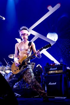 a shirtless man playing guitar on stage