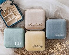 four personalized jewelry cases sitting on top of a basket with wedding rings in them