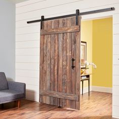 a living room with a gray couch and wooden sliding barn door in the middle of it