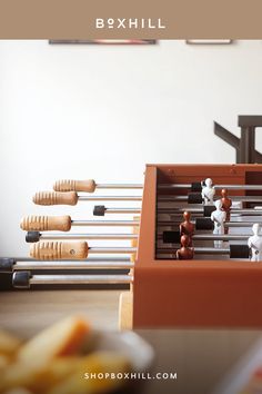 A close-up view of a brown outdoor football table with wooden handles placed near a white wall