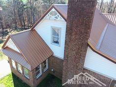 an aerial view of a brick house with a metal roof and white trim on it