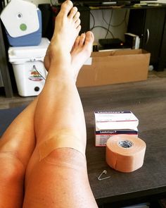 a person's legs with bandages on top of a table next to a roll of tape