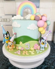 a birthday cake decorated with cartoon characters and balloons