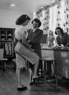 an old black and white photo of women standing around a kitchen island with clothes on it