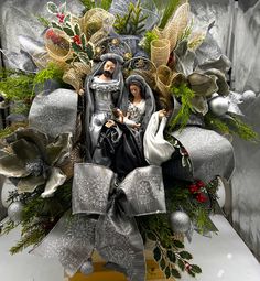 a nativity scene is displayed on a table with silver cloths and greenery