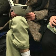 a man sitting down reading a book while wearing headphones