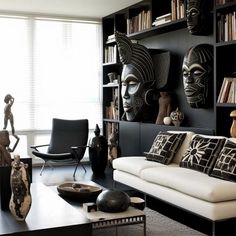 a living room filled with furniture and bookshelves covered in african mask masks on the wall