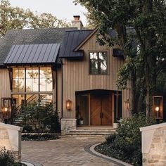 a large house with lots of windows and lights on the front door, surrounded by trees