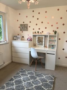 a white desk sitting under a window next to a wall with polka dots on it