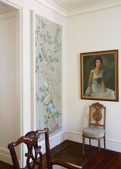 a chair sitting in front of a painting on the wall next to a wooden floor