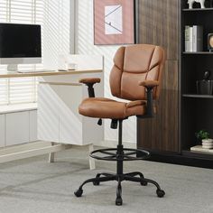 a brown office chair sitting in front of a desk with a computer monitor on it