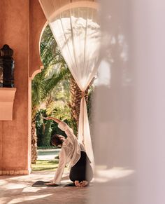 a woman is doing yoga on the floor in front of an open window with curtains