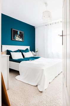 a bed room with a neatly made bed and blue walls