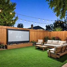 a backyard with grass, couches and a projector screen