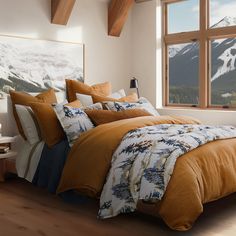 a bedroom with a large window overlooking the mountains and snow covered peaks is pictured in this image