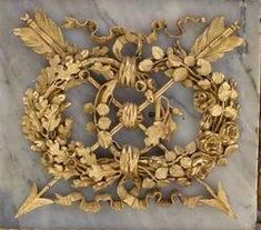 an ornate gold wreath on a marble block in the shape of a square with leaves and flowers