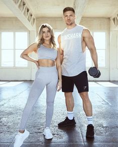 a man and woman posing for a photo in gym wear with dumbs on their feet