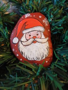 a rock with a santa clause painted on it sitting in the branches of a tree