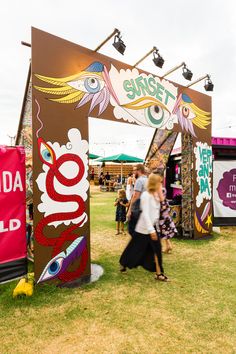 people are walking around in the grass at an outdoor music festival with signs and banners