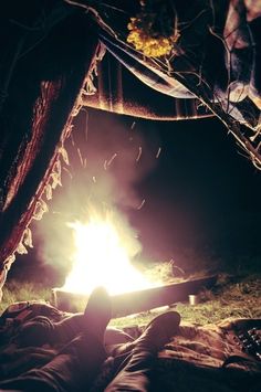 a person laying down in front of a campfire