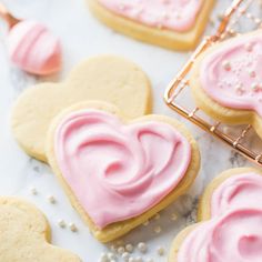 some heart shaped cookies with pink frosting on them