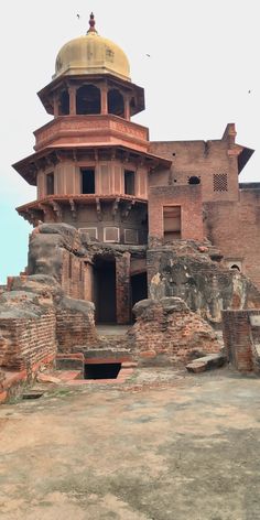 an old brick building with a gold dome on the top and two small steps leading up to it