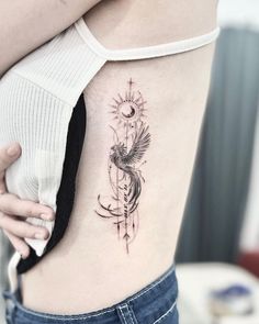 a woman's lower back tattoo with an arrow and bird on the left side