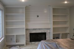 a living room with white bookcases and a fireplace