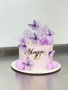 there is a pink cake with purple butterflies on it