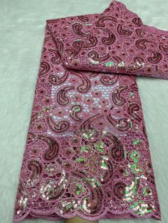 a pink and green sequinized scarf laying on top of a white furnishing