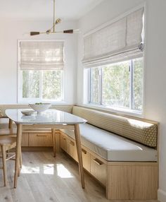 a kitchen with a table, bench and window in the corner on the wall next to it