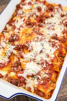 a casserole dish with meat, cheese and sauce in it on a wooden table