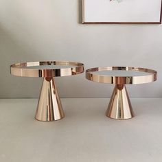 two round metal trays sitting on top of a white table next to each other