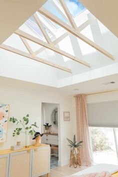 a bedroom with a skylight above it and a bed in the foreground next to a window