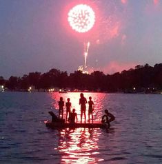 people on a boat watching fireworks go off in the sky