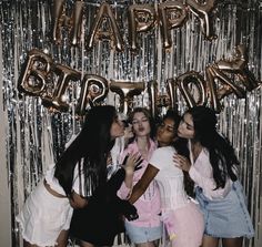 group of young women standing in front of foil balloons with the word happy birthday written on it