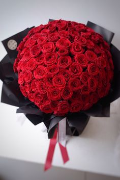 a large bouquet of red roses is wrapped in black paper