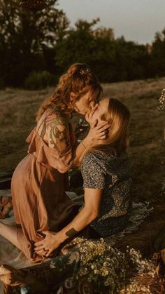 two women sitting on the ground kissing each other