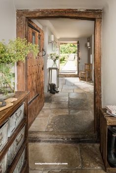 an open door leading to a hallway with stone floors and wooden doors on both sides