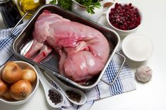 raw chicken in a pan surrounded by ingredients and utensils on a white table